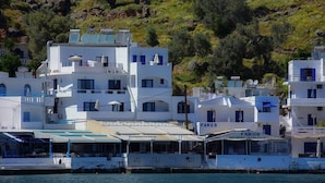 Um edifício costeiro com vários andares, um letreiro com 'Faros Market' e um barco atracado em frente.