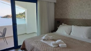 Quarto de hotel com uma cama, mesa de cabeceira e vista para o mar.