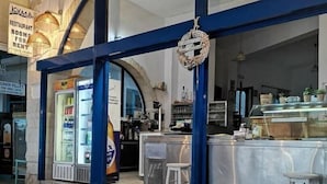 Um restaurante com esquema de cores azul e branco, um letreiro indicando quartos para alugar e um balcão com banquetas.