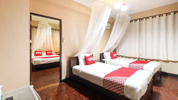 A hotel room with two beds, each with a canopy bedspread and pillows with 'OYO' branding. - OYO 369 Micasa Guesthouse (Chiang Mai)