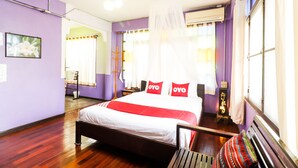 A bedroom with a bed, a bench, a nightstand, and a window with curtains. - OYO 369 Micasa Guesthouse (Chiang Mai)