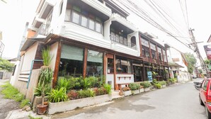 A two-story building with a balcony, potted plants, and a parked car. - OYO 369 Micasa Guesthouse (Chiang Mai)