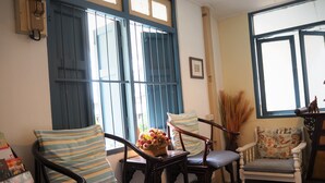 A cozy room with a wooden chair, a cushioned bench, and a small table with a vase of flowers. - Stay With Me Guesthouse (Chiang Mai)