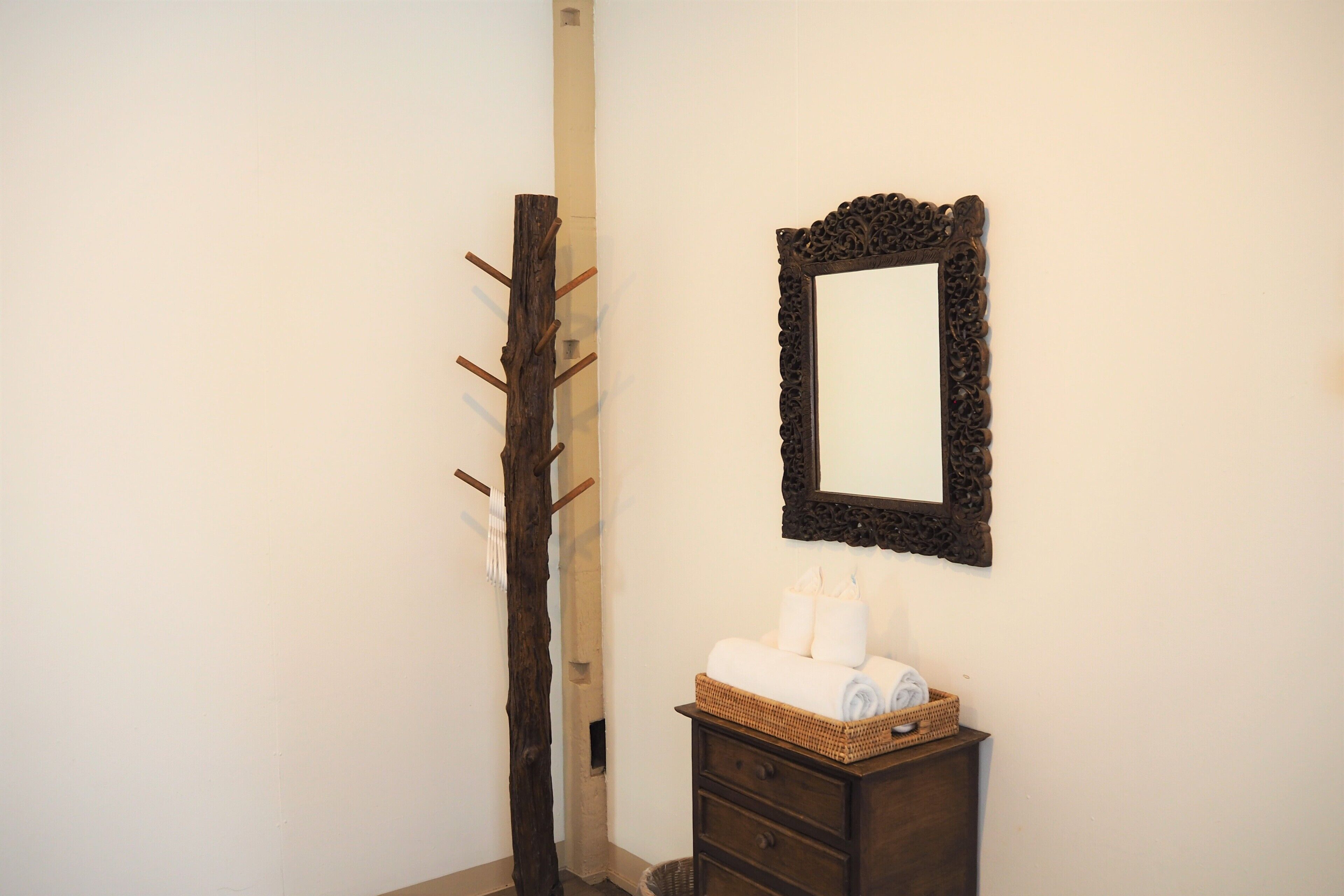 A bathroom with a wooden cabinet, a mirror, and a towel rack.