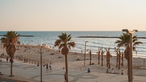 Una playa con palmeras, gente relajándose y un mar tranquilo.