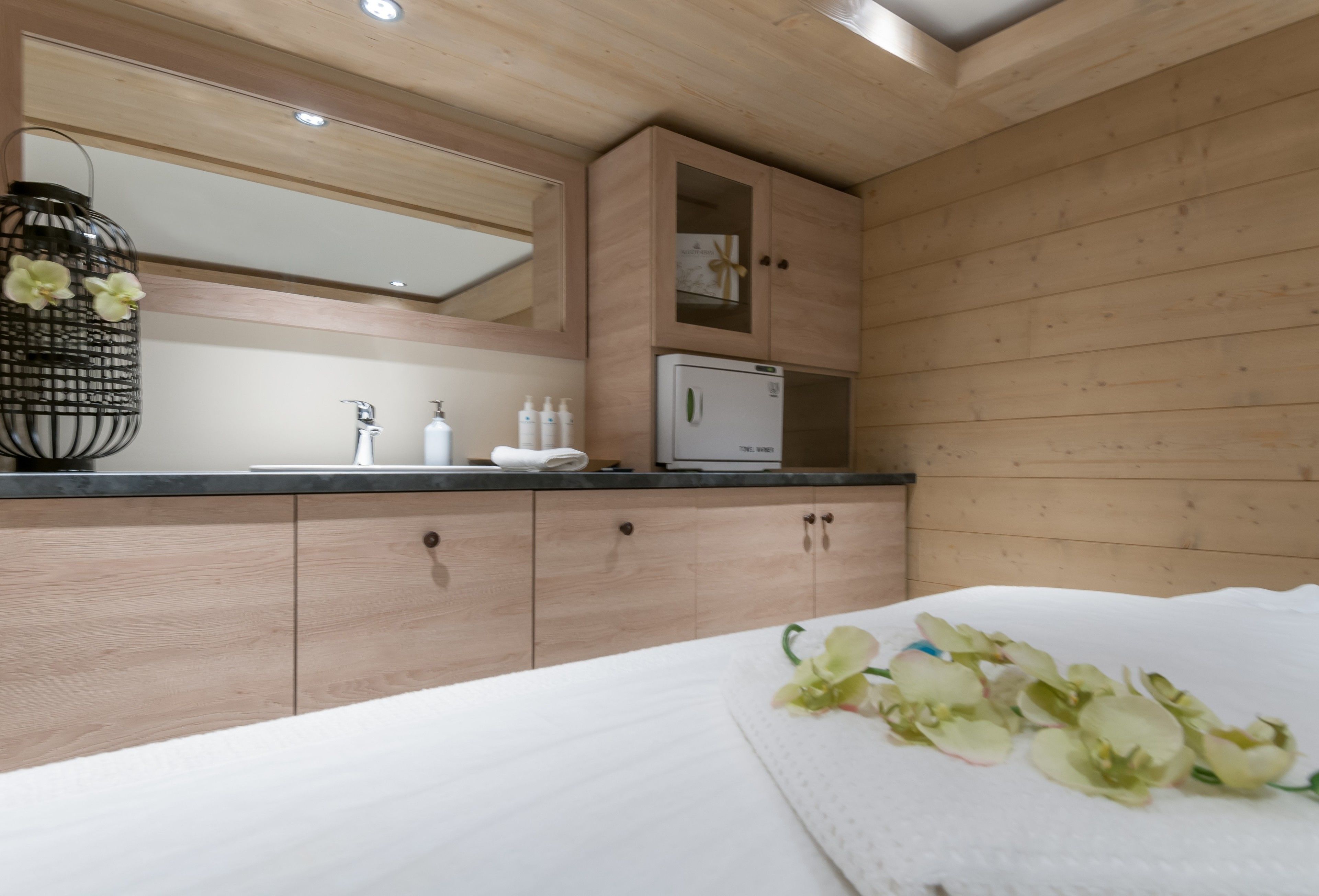 Ein modernes Badezimmer mit Holzsäcken, einem Spiegel, einem Waschbecken und einer weißen Arbeitsplatte.
