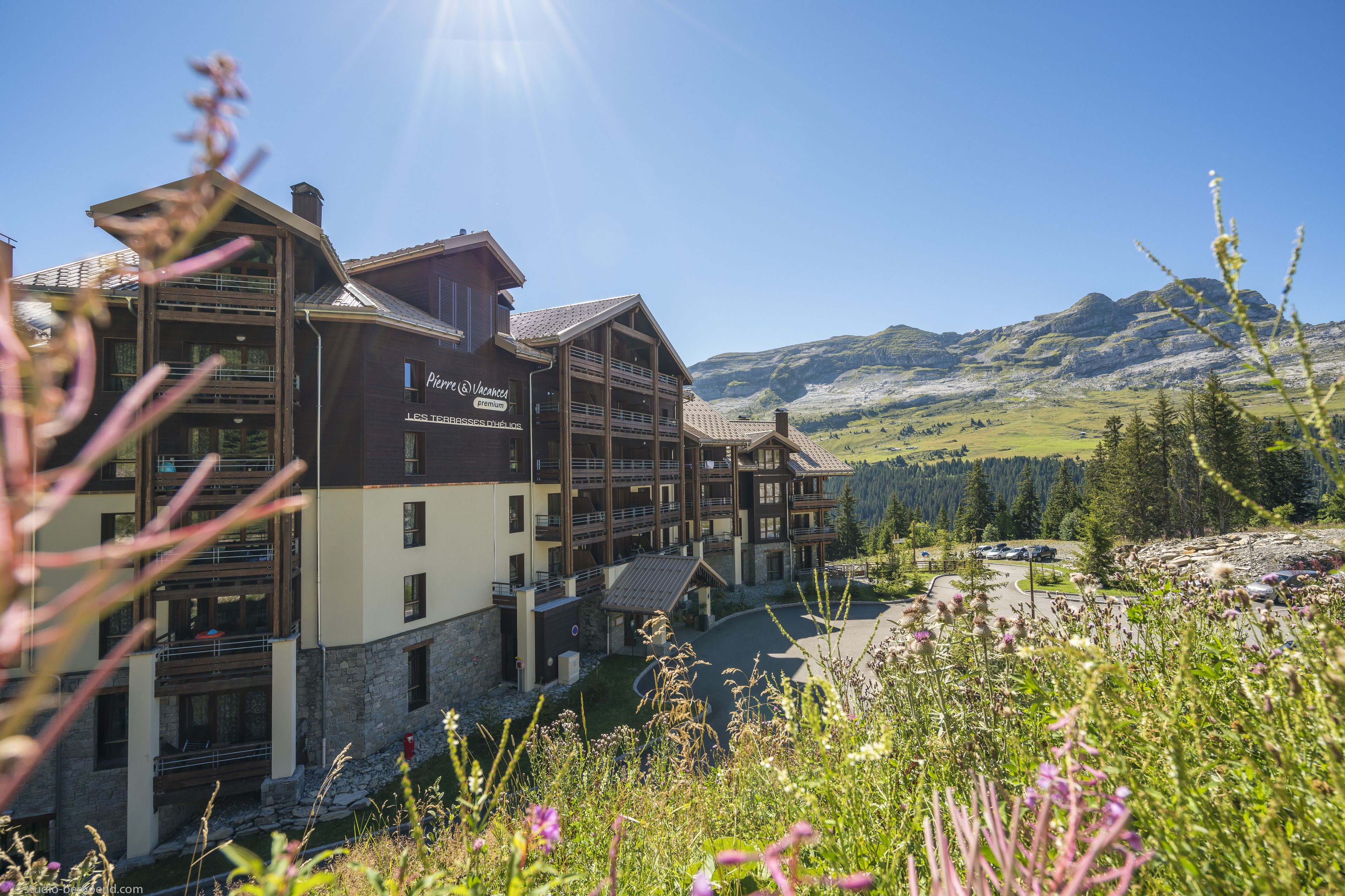 A multi-story lodge with a stone facade, multiple balconies, and a view of the surrounding mountains.