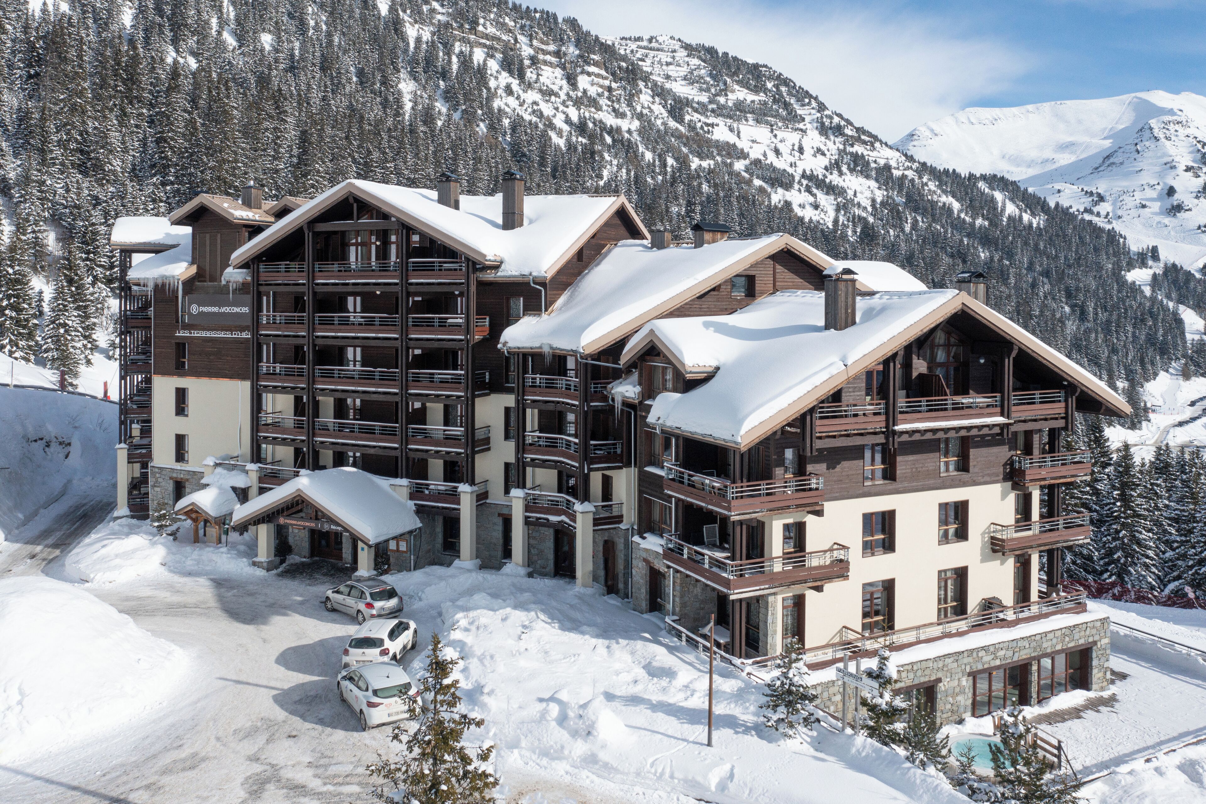 A multi-story ski resort building with balconies and a pool area.