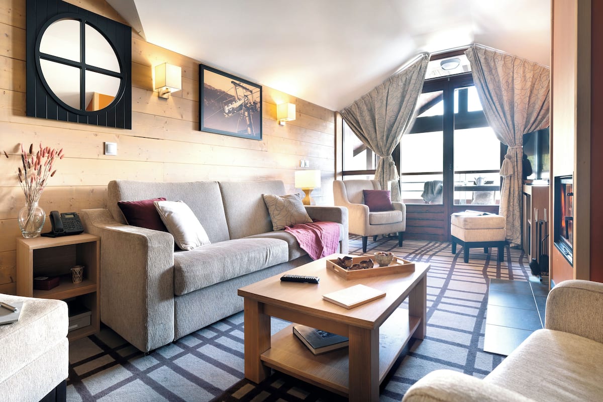 A cozy living room with a sofa, armchairs, a coffee table, and a fireplace.