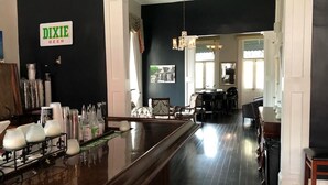 A bar area with a sign reading "DIXIE BEER", a polished wooden bar counter, and a seating area with chairs and a table. - Lafitte Hotel & Bar (New Orleans)