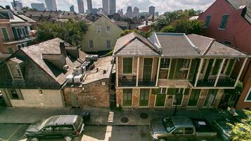 A residential area with a two-story house featuring a balcony, a garage, and a street view with parked cars.