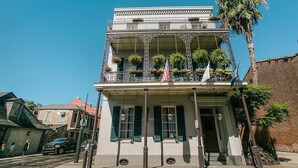 A two-story building with a balcony, large windows, and a flag. - Lafitte Hotel & Bar (New Orleans)