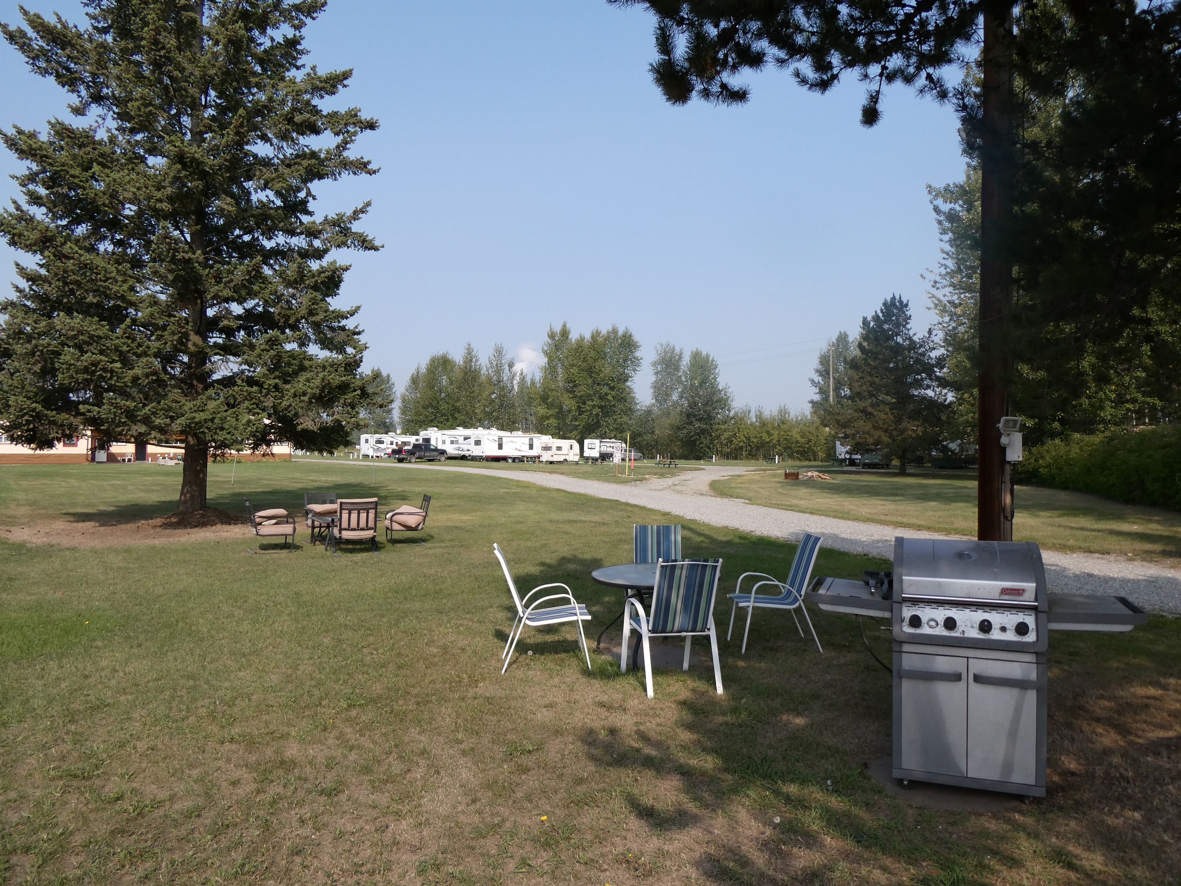 Un camping con una parrilla, una mesa de picnic y sillas.