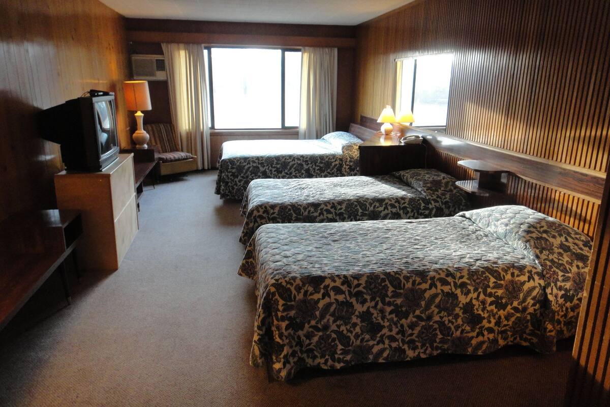 A hotel room with two beds, a TV, a desk, and a lamp.