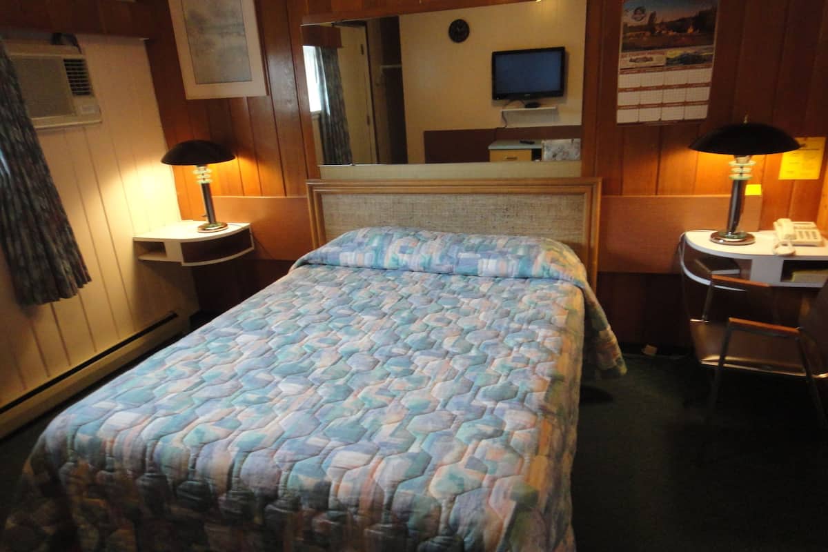 A hotel room with a bed, two bedside tables with lamps, a television, and a mirror.