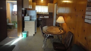 Cocina compacta con refrigerador, microondas y pileta. Hay una zona de comedor con una mesa y sillas.