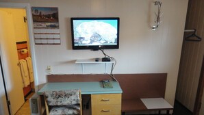 Una habitación pequeña con un escritorio, una silla y un televisor montado en la pared.
