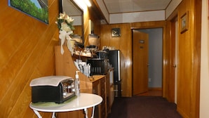 A hotel lobby with a wooden floor, a reception desk, a coffee machine, and a mirror. - Airport Inn Motel & RV Park (Quesnel)