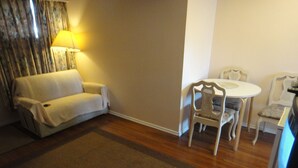 Una habitación de hotel con sofá, una mesa de comedor con sillas y una lámpara.