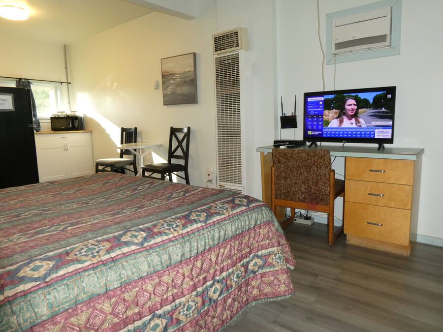 Une chambre à coucher avec un lit, un bureau, une chaise, une télévision et une fenêtre.