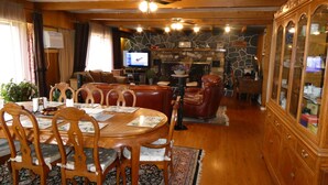 A dining area with a wooden table and chairs, a fireplace, and a television in the background. - Airport Inn Motel & RV Park (Quesnel)
