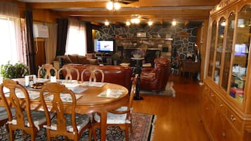 A dining area with a wooden table and chairs, a fireplace, and a television in the background.