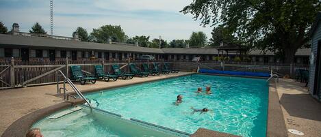 A swimming pool with lounge chairs and a covered area.