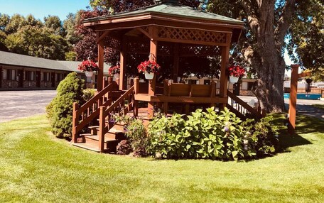 A gazebo with a wooden structure, steps, and potted plants.