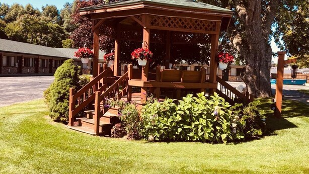 A gazebo with a wooden structure, steps, and potted plants. - Viking Arms Inn (Ludington)