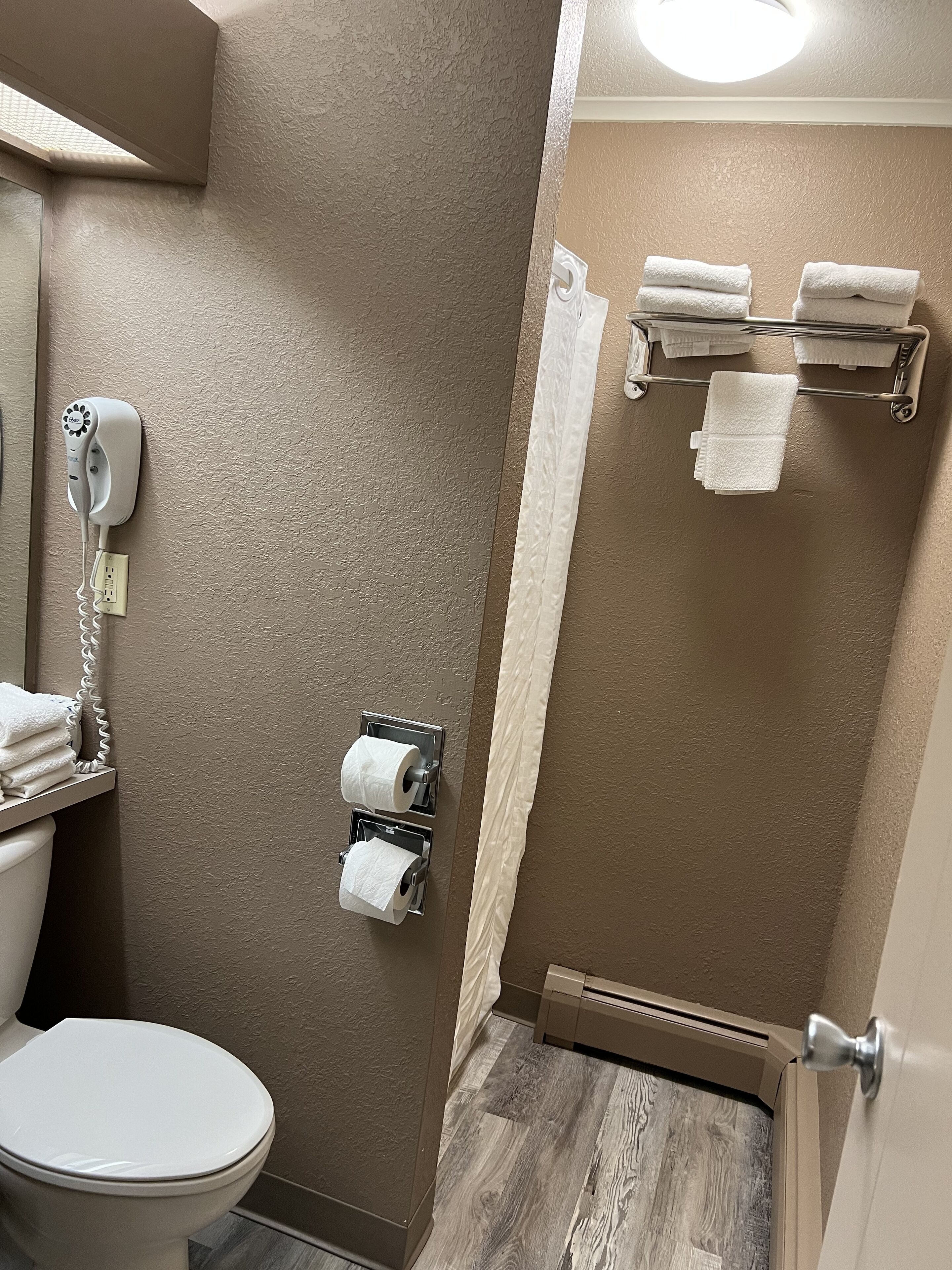 A bathroom with a toilet, a hairdryer, and a towel rack.