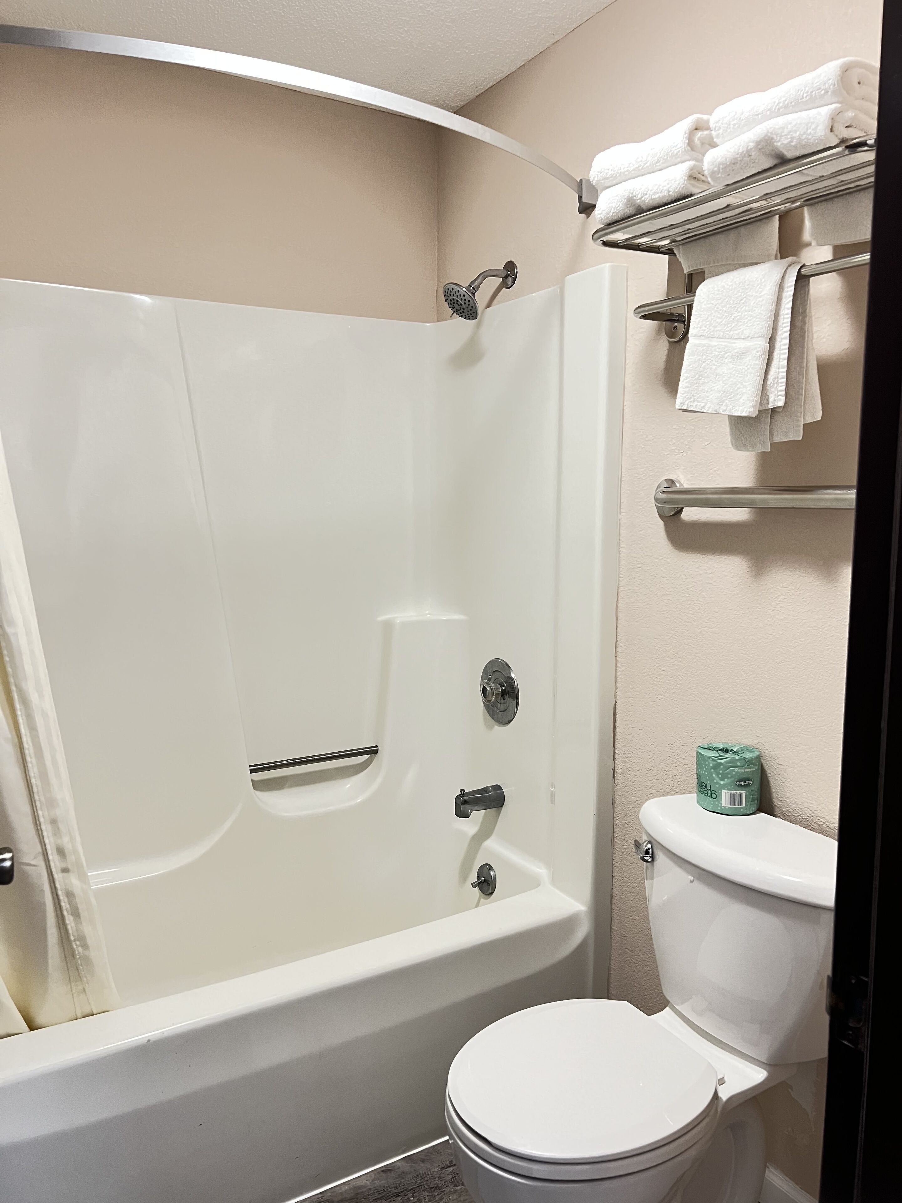 Un baño con bañera, inodoro y un estante con toallas.