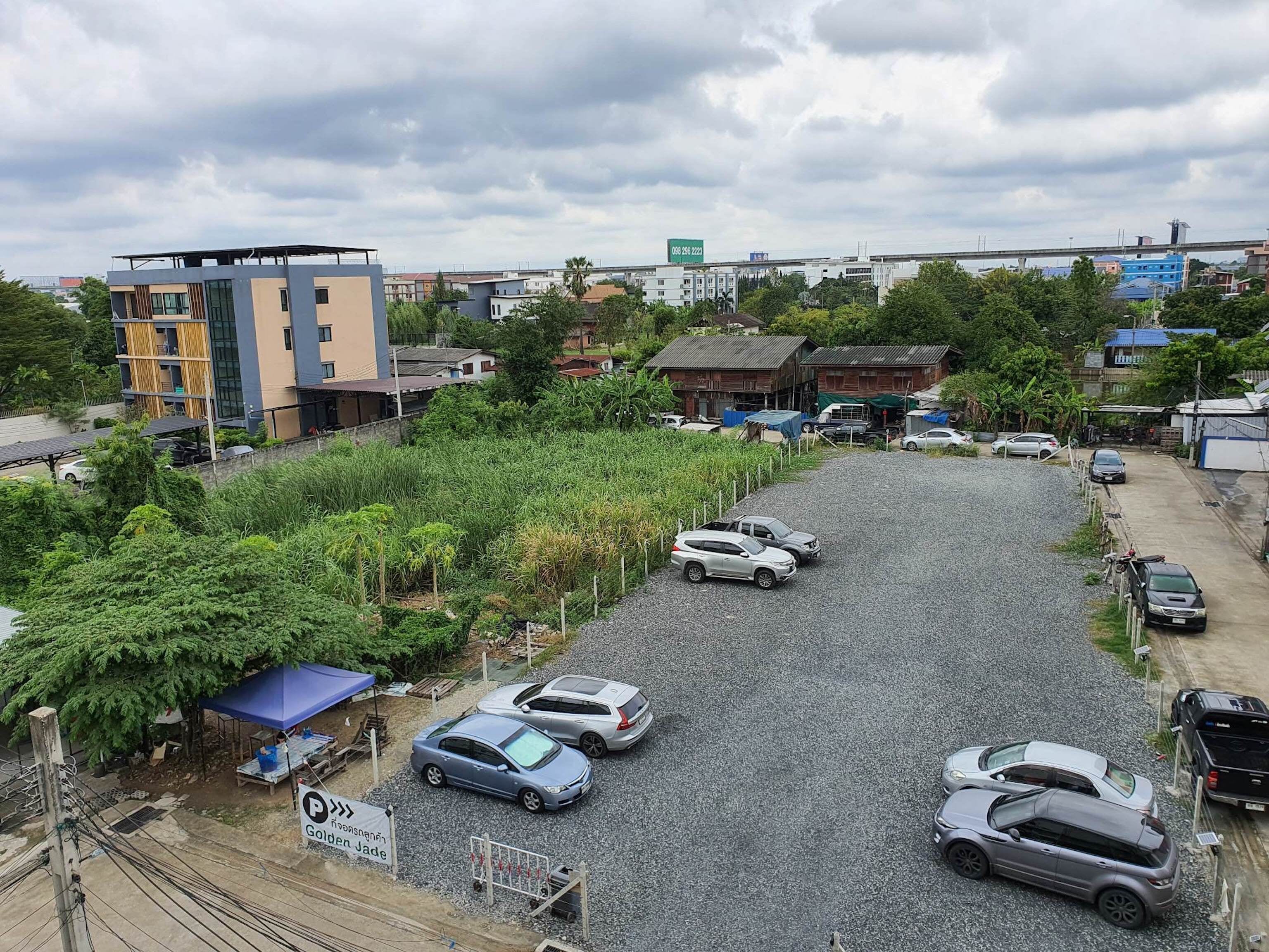 A parking lot with several cars, a sign for Golden Jade, and buildings in the background.