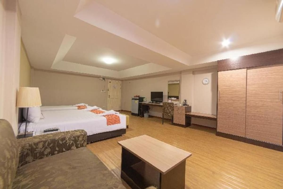 Una habitación de hotel con cama, escritorio, silla, sofá y armario.