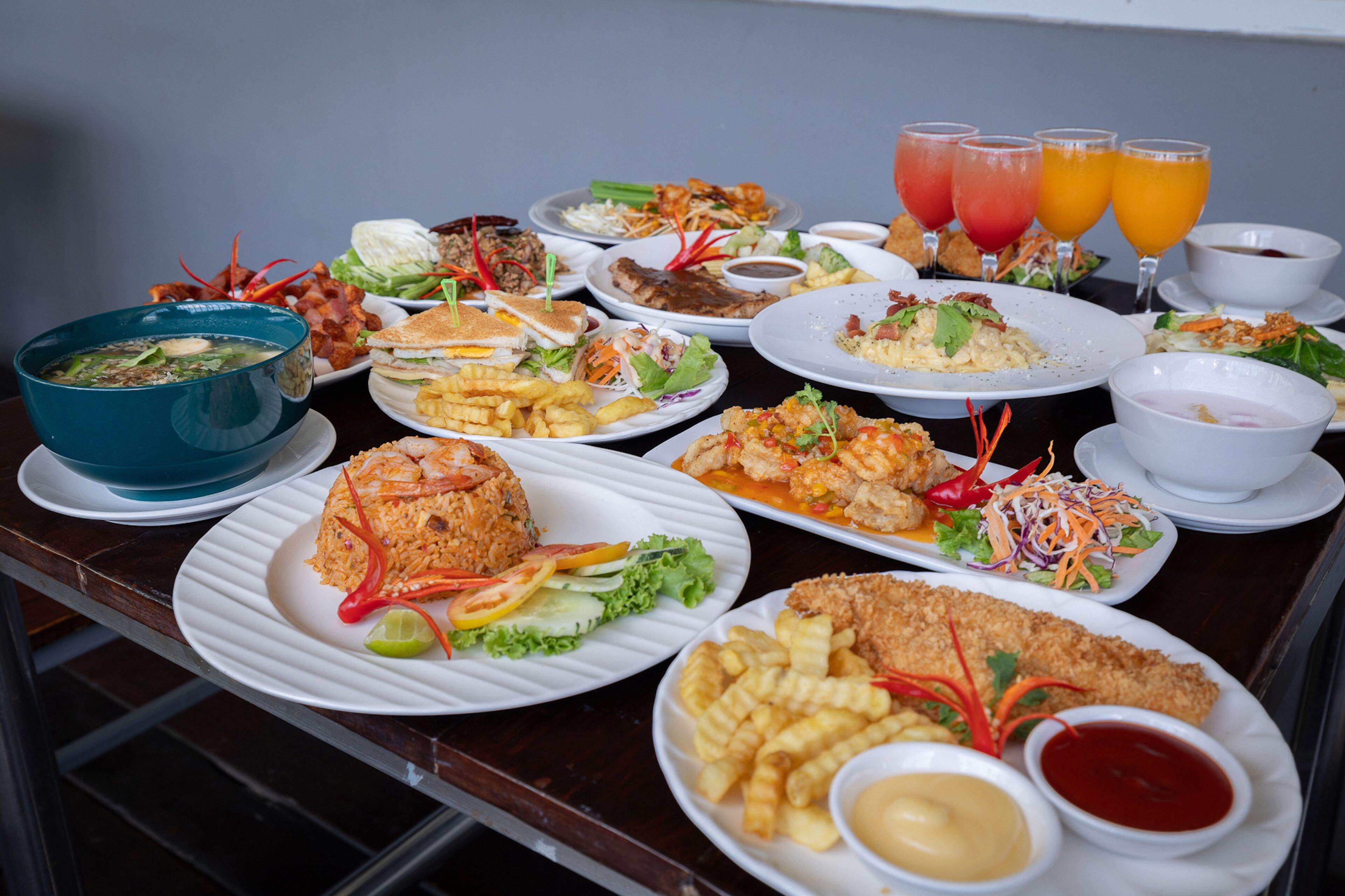 A table with various dishes including fried items, salads, and beverages.