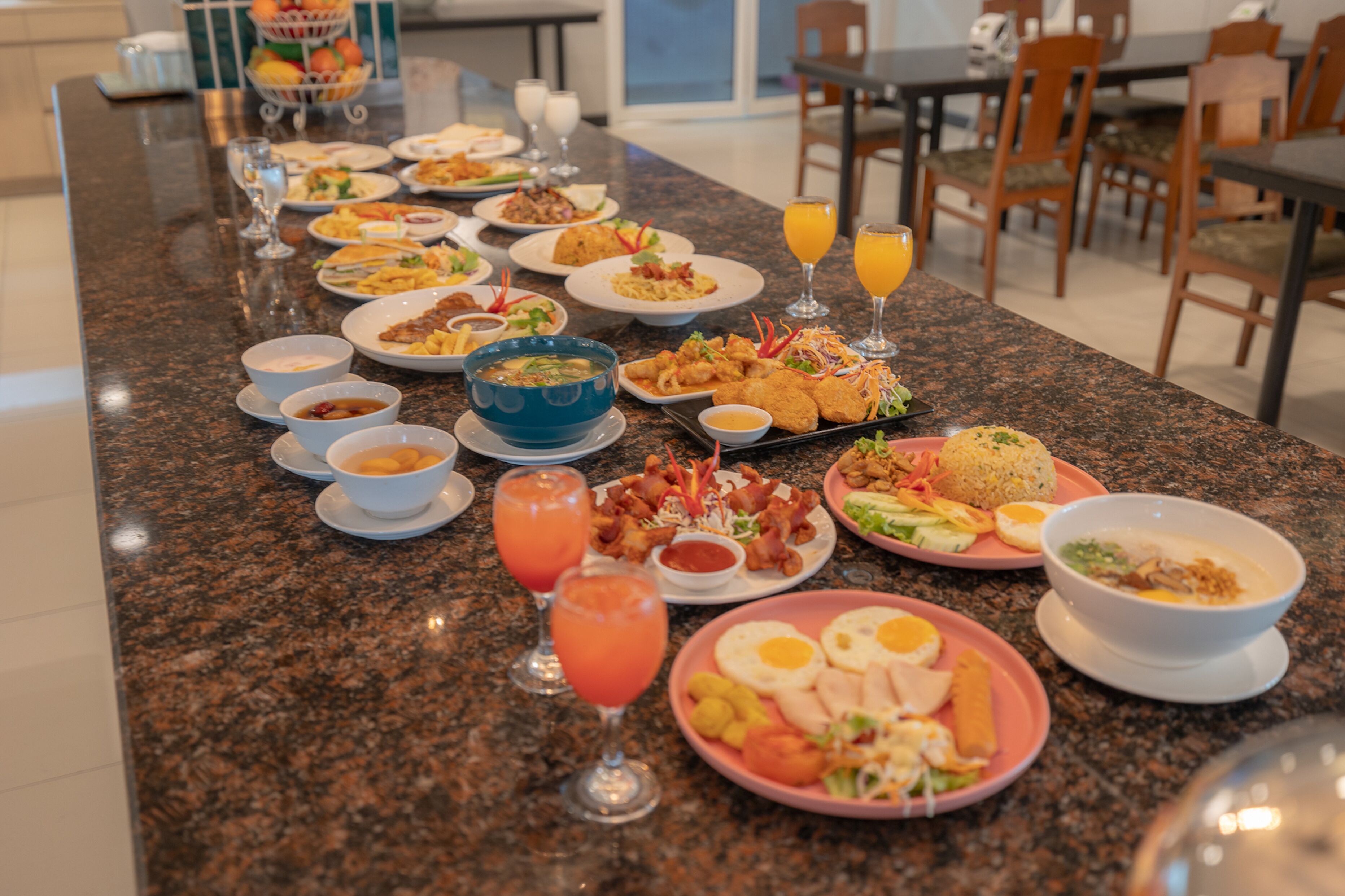 Een ontbijtbuffet met diverse gerechten, drankjes en een fruitmand.