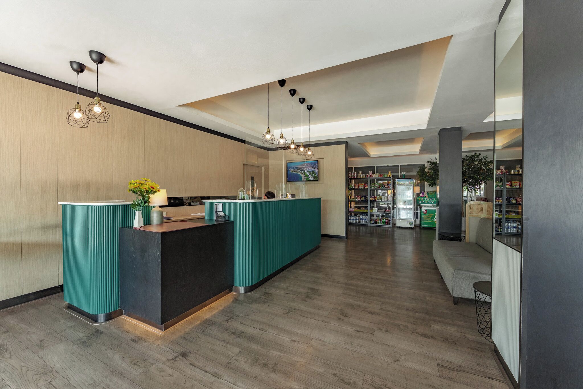 A reception area with a teal counter, wooden flooring, and pendant lighting.