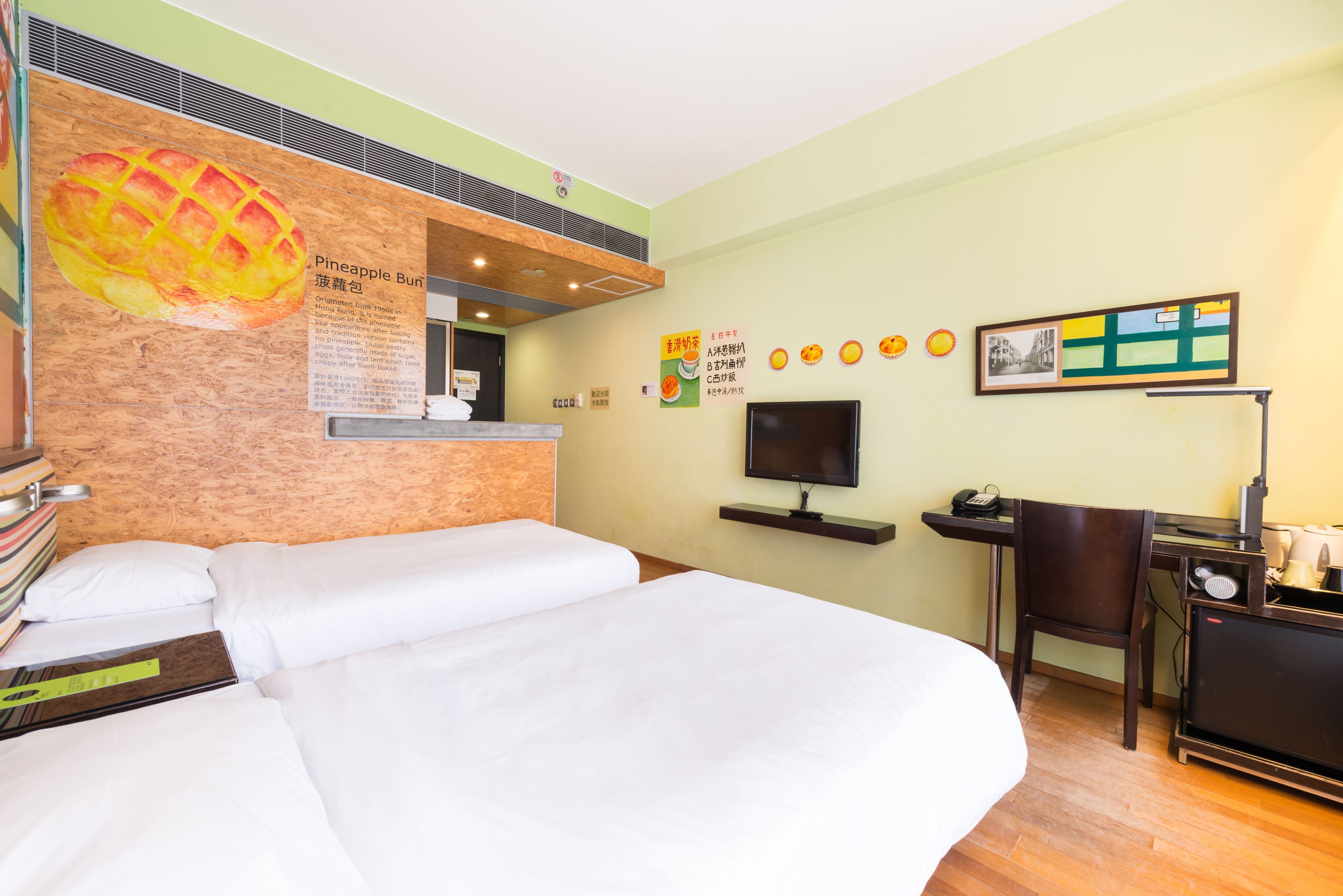 A hotel room with a bed, a desk with a computer, a chair, and a television.