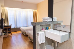 A hotel room with a bed, a desk, a chair, a bathroom with a sink and mirror, and a window with curtains. - Y Loft Youth Square (Hong Kong)
