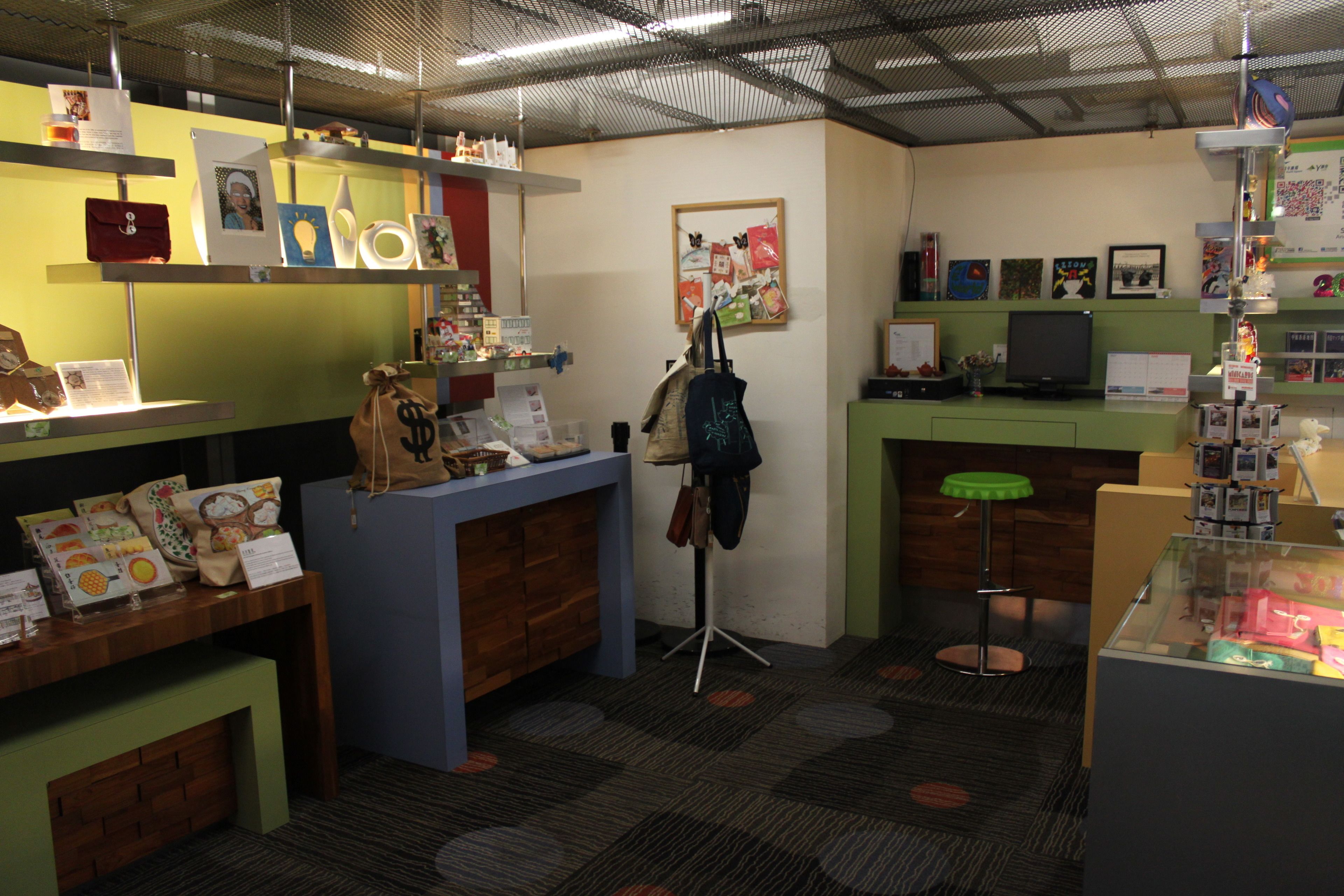 Una habitación con un escritorio de madera, una silla azul, un taburete verde y una vitrina de vidrio.
