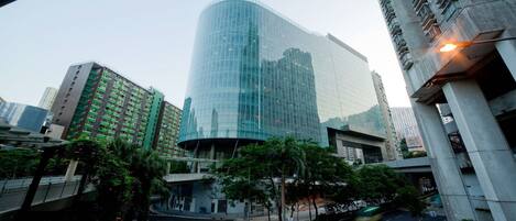 A modern building with a curved glass facade, surrounded by other high-rise buildings and palm trees.