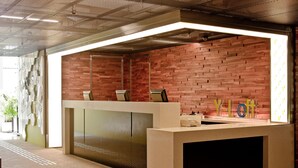 Un mostrador de recepción con un fondo de pared de ladrillo, diseño moderno y una señalización que dice "YLOFT".