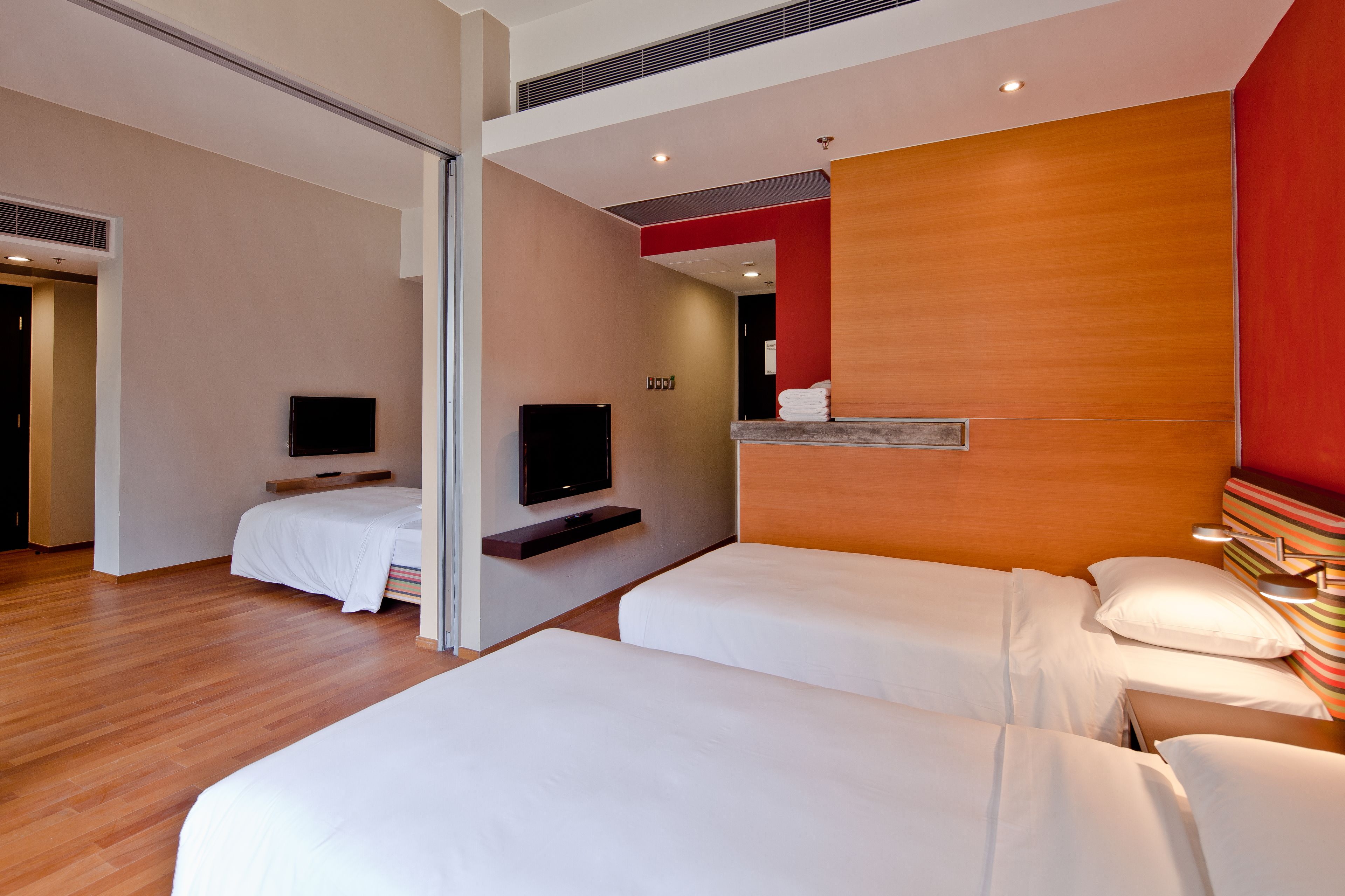 Une chambre d’hôtel avec deux lits, une télévision et un mur décoratif en bois.