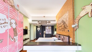 Habitación de hotel con cama, escritorio y decoración de pared con temática de jirafa.