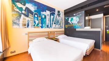 Quarto de hotel com duas camas, um grande mural abstrato na parede e cabeceira de madeira.