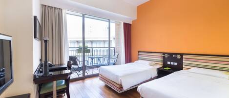 A hotel room with two beds, a desk with a chair, a TV, and a balcony with a table and chairs.
