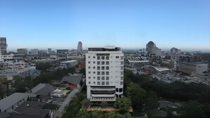 Um hotel moderno com uma torre central, rodeado por outros edifícios e vegetação.