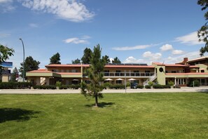 A hotel with a red roof, multiple floors, and a central courtyard with a tree.