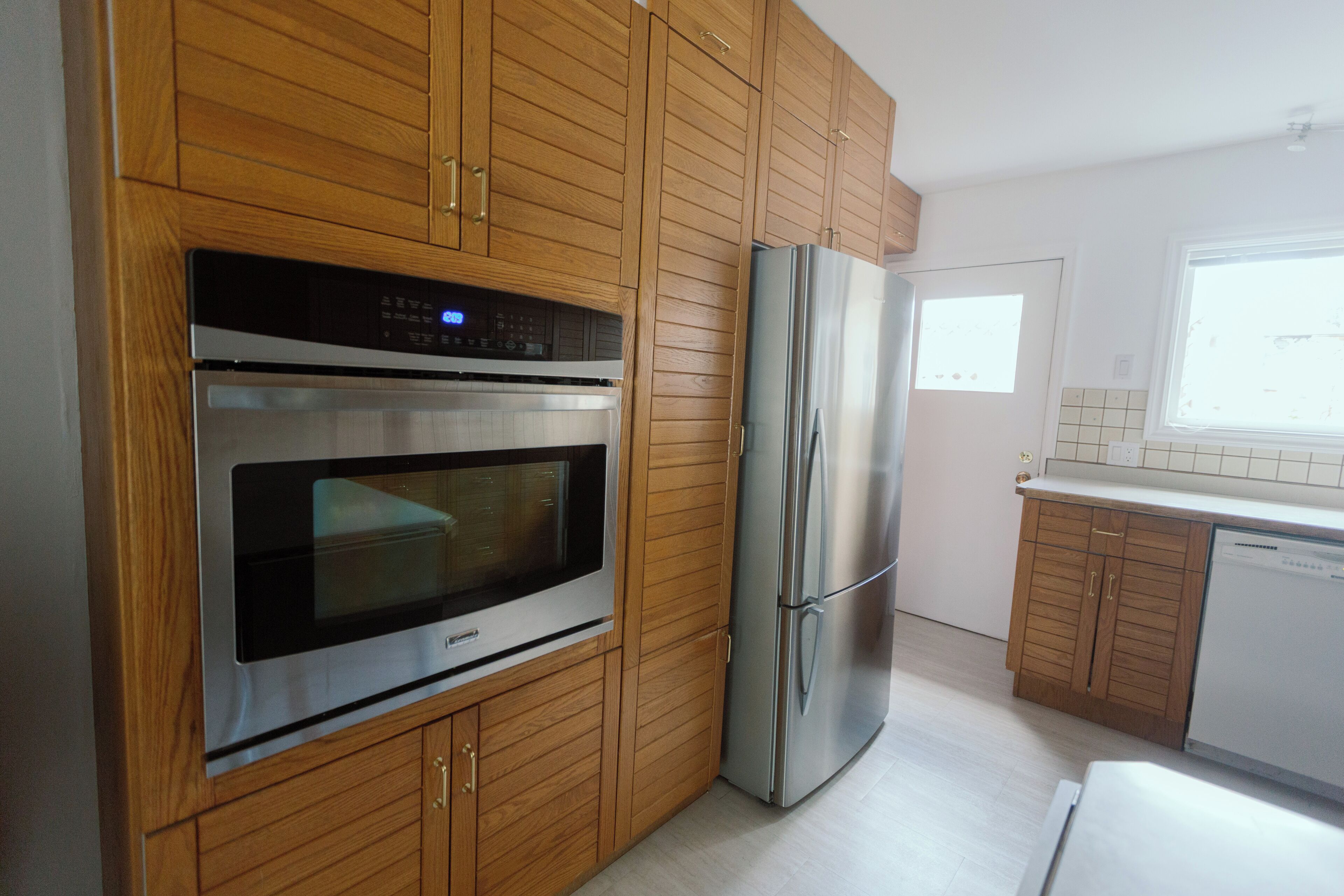Una cocina con armarios de madera, horno de acero inoxidable y refrigerador.