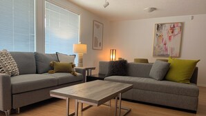 A modern living room with two grey sofas, a wooden coffee table, and a floor lamp. - Waterfront Inn (Penticton)