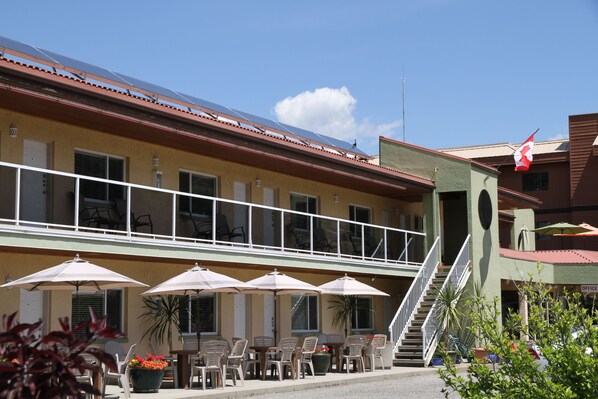A building with a balcony, outdoor seating with umbrellas, and a flag.